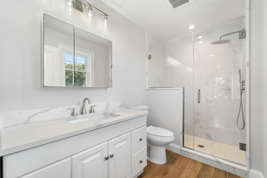 White bathroom renovation with new tile and vanities by general contractors in Long Beach NY