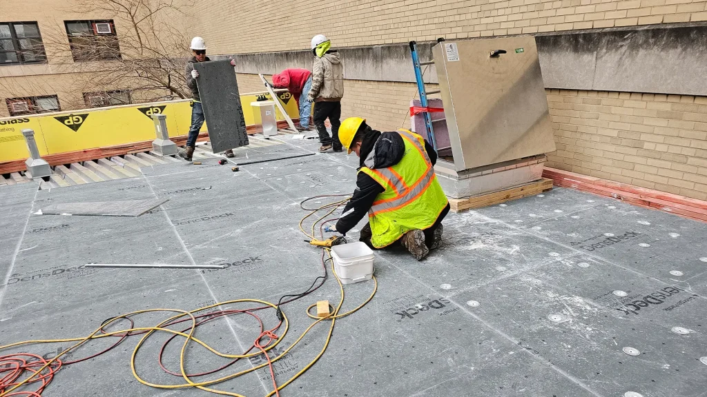 Roofer applying sealant during emergency roof repair on Long Island flat roof
