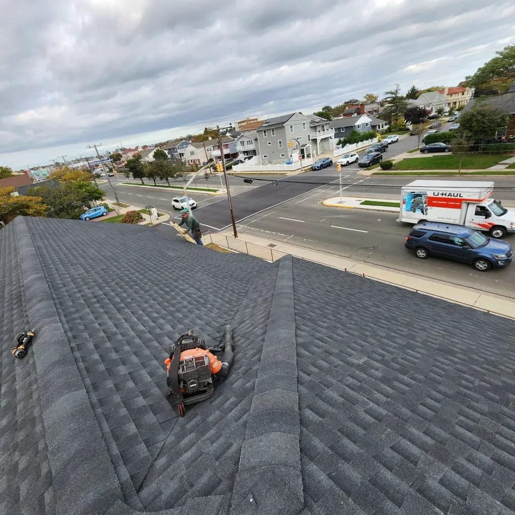 Roofer fixing damaged shingles on a Long Beach home roof after a storm